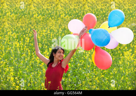 Junge Frau mit Luftballons in einem Feld Stockfoto