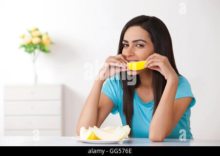 Porträt der schönen jungen Frau Scheibe Melone zu Hause essen Stockfoto