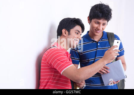 Glücklich männlichen Studenten mit Handy gegen die Wand Stockfoto