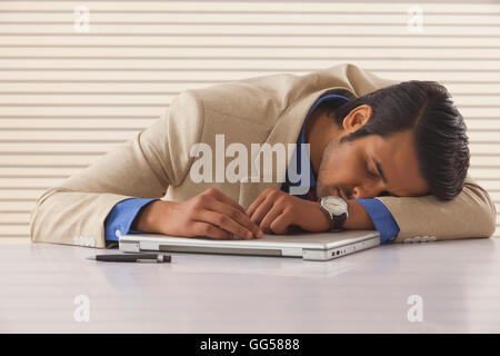 Junger Geschäftsmann schlafen auf Laptop am Schreibtisch im Büro Stockfoto