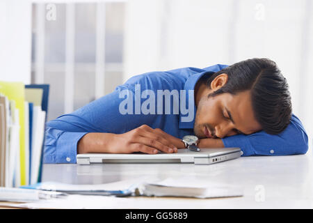 Junger Geschäftsmann auf Laptop am Schreibtisch schlafen Stockfoto