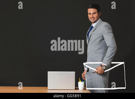 Digital erzeugte Bild des indischen Geschäftsmann hält e-Umschlag im Büro Stockfoto