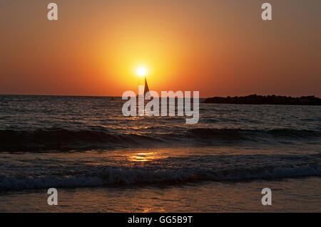 Tel Aviv, Israel, Naher Osten: der Strand, ein Segelboot und das Mittelmeer bei Sonnenuntergang am Ende eines wunderschönen Sommertag Stockfoto