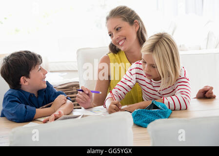 Mutter und Kinder Hausaufgaben auf Tisch Stockfoto