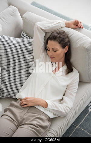 Reife Frau entspannend auf couch Stockfoto
