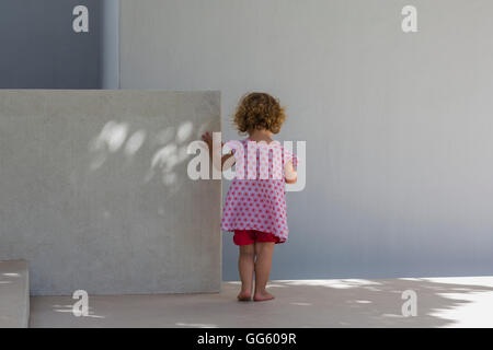 Ansicht von hinten von einem Babymädchen stehend gegen eine Wand Stockfoto