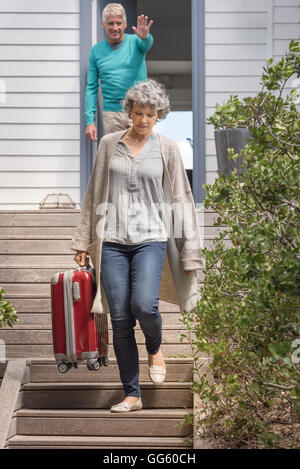 Happy senior woman winken zu seiner Frau mit Koffer auf Treppe Stockfoto