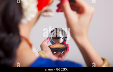 Nahaufnahme des Bharatanatyam-Tänzerin, die Anwendung von Mascara auf grauem Hintergrund Stockfoto