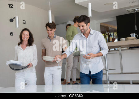 Glückliche Freunde tragen Gerichte zum Mittagessen zu Hause Stockfoto