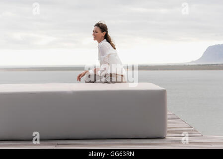 Glücklich Reife Frau sitzen auf Ottomane am Seeufer Stockfoto