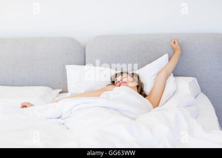 Verschlafene Frau aufwachen und mit einem langen Gähnen Stockfoto
