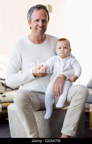 Porträt der glückliche Vater mit seiner niedlichen Baby-Tochter im Wohnzimmer Stockfoto