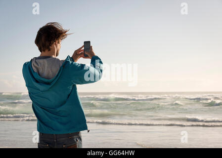 Glücklich Jüngling unter Bild mit Kamera-Handy am Strand Stockfoto