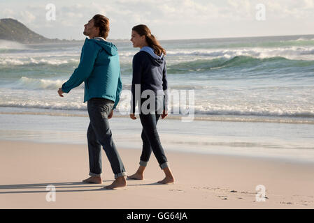Glückliches junges Paar zu Fuß am Strand Stockfoto