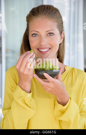 Porträt einer glücklich schönen Frau essen Trauben Stockfoto