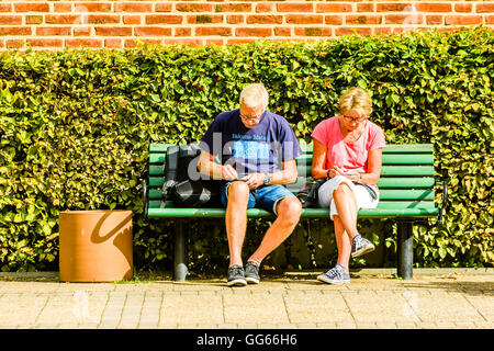 Ystad, Schweden - 1. August 2016: Echte Menschen im Alltag. Zwei hochrangige Personen kratzen Lottoscheine auf einer Bank. Stockfoto