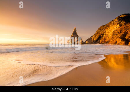 Goldenen Reflexen von den Klippen am Strand von Praia da Ursa bei Sonnenuntergang, vom Meer umspült, Cabo da Roca, Colares, Sintra, Portugal Stockfoto