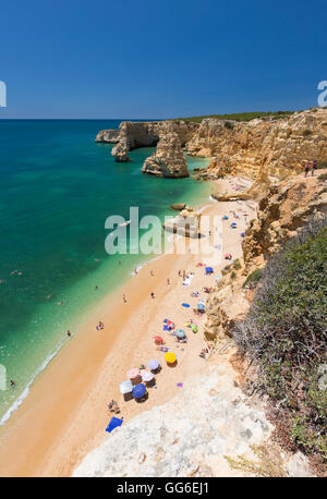Touristen am Sandstrand Praia da Marinha umgeben von türkisblauem Meer, Caramujeira, Gemeinde Lagoa, Algarve, Portugal Stockfoto
