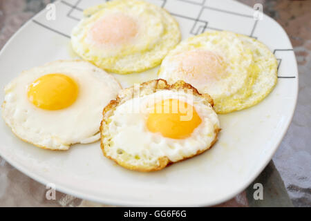 Vier Spiegeleier auf einer Platte auf einem Glastisch Stockfoto