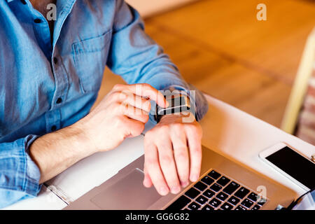 Mann, der Arbeiten von zu Hause am Laptop, trägt smartwatch Stockfoto