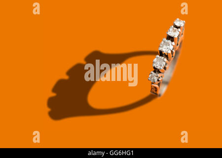 Diamant-Ring mit Schatten über einem orangefarbenen Hintergrund Stockfoto