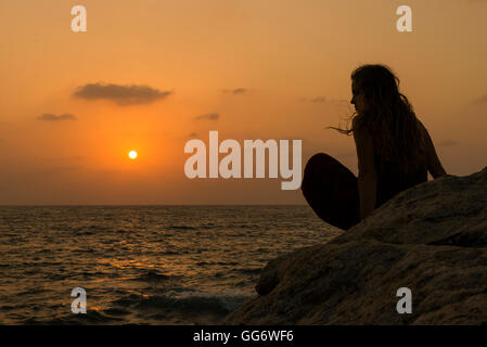 Eine Frau genießt einen Sonnenuntergang am Strand von Om in Gokarna, Indien. Stockfoto