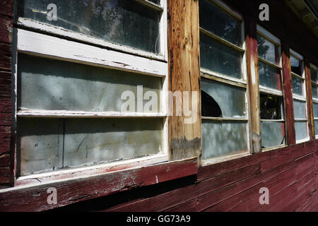 Zerbrochene Fensterscheiben auf der Seite eine alte, hölzerne Scheune im ländlichen Amerika. Stockfoto