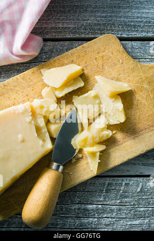 Den Parmesan mit Messer auf Schneidebrett. Stockfoto