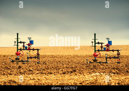 Erdgas Bohrlochköpfe nahe beieinander in einem gepflügten Maisfeld. Stockfoto