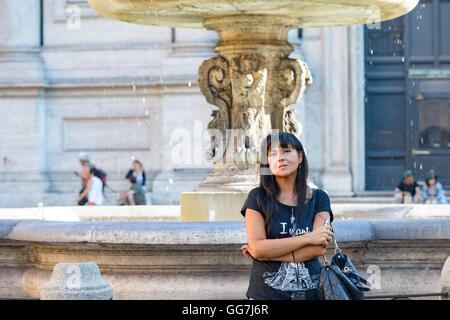 Mädchen posiert unter einem Brunnen in Rom, Italien