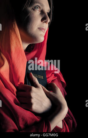 Frau mit einer Bibel in der Nacht. Auf schwarzem Hintergrund isoliert Stockfoto