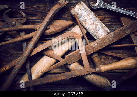 Grunge alte verrostete Werkzeuge auf einer hölzernen Hintergrundverarbeitung (Prozess-) Stockfoto