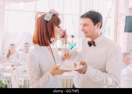 Nahaufnahme des lächelnden Bräutigam seine Braut mit einer Hochzeitstorte, drinnen zu füttern Stockfoto