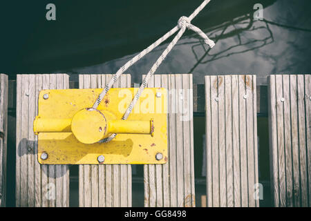 Vintage getönten alte gelb Festmacher Poller auf hölzernen Pier, geringe Schärfentiefe. Stockfoto