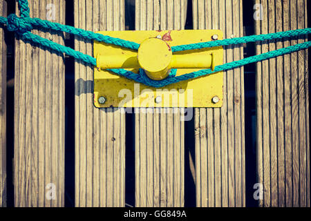 Vintage getönten alte gelb Festmacher Poller auf hölzernen Pier, geringe Schärfentiefe. Stockfoto