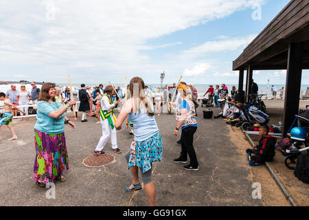 Frauen, die beide von Morris Seiten und Mitglieder der Öffentlichkeit, tanzen die 'gun Dance" mit hölzernen Stäben als Waffen, während auf Broadstairs Harbour Jetty. Stockfoto