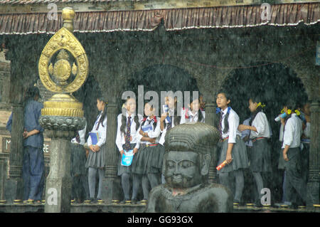 KATHMANDU, ca. AUGUST 2012 - junge Studenten Unterschlupf vor dem Monsunregen in einem Tempel, ca. August 2012 in Kathmandu. Stockfoto