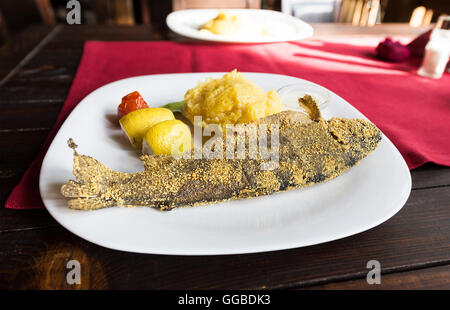 Foto von gekochten Forellen Fisch auf einem Teller mit Zitrone, Sahne und Mamaliga Maismehl. Rumänische traditionelles Gericht. Stockfoto