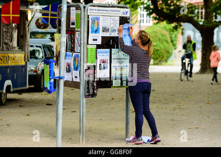 Ystad, Schweden - 1. August 2016: Echte Menschen im Alltag. Frau pin eine Nachricht auf einem öffentlichen Forum in der Stadt. Stockfoto