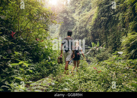 Rückansicht des jungen Paares zu Fuß durch Wald mit ihren Schuhen in der hand. Mann und Frau im Wald wandern. Stockfoto