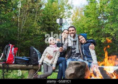 Familie mit Smartphone unter Selfie nahe am Lagerfeuer Stockfoto