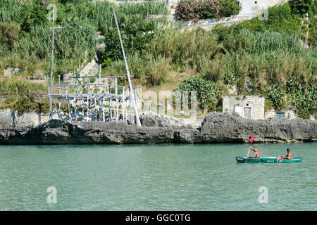 Vieste, Italien - 29. Juni 2016: Menschen paddeln Kanu vor einem Trabucco in Vieste in Apulien, Italien. Stockfoto