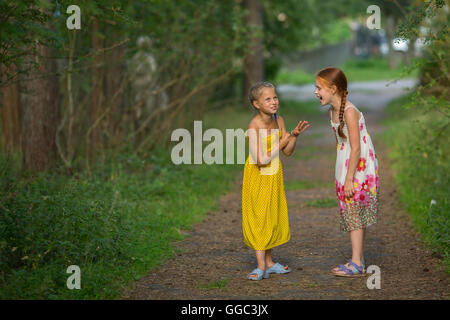 Zwei niedliche kleine Mädchen sprechen lebhaft steht in einem Park. Stockfoto