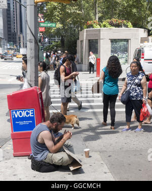 Obdachloser sitzt auf dem Bürgersteig auf der Suche nach Hilfe auf 40. St. von Bryant Park in Midtown Manhattan 6th Ave. Stockfoto