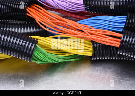 Buntes elektrische Kabel und Leitungen in schwarzem Kunststoff Wellrohren in Elektroinstallation auf Metalloberfläche als Hintergrund verwendet Stockfoto