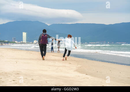 Danang, Vietnam - 20. Februar 2016: Junges Paar vorbei und Hand in Hand am China Beach in Danang, in Vietnam. Kein Gesicht Stockfoto