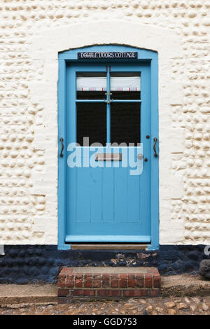 Blaue Tür in einer gepflasterten Wand mit Schild oben Stockfoto