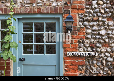 Blaue Tür in einer gepflasterten Wand mit Schild mit der Aufschrift Pflastersteine Stockfoto