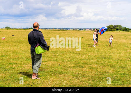 Kaseberga, Schweden - 1. August 2016: Echte Menschen im Alltag. Man Drachen in einem Feld mit Wolken im Hintergrund Stockfoto