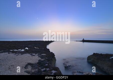 Langzeitbelichtung Foto auf das Meer und einem Fischer auf einem Pier am Seven Mile Beach in Grand Cayman, Kaimaninseln (Karibik). Stockfoto